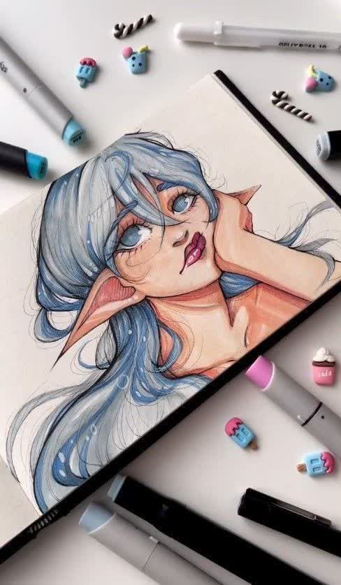 Anime-style art of a fantasy character with blue hair and pointed ears in a sketchbook, surrounded by markers and cute erasers.