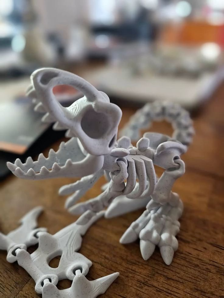 3D printed dinosaur skeleton model on a wooden table, showcasing intricate bone details in a realistic pose.