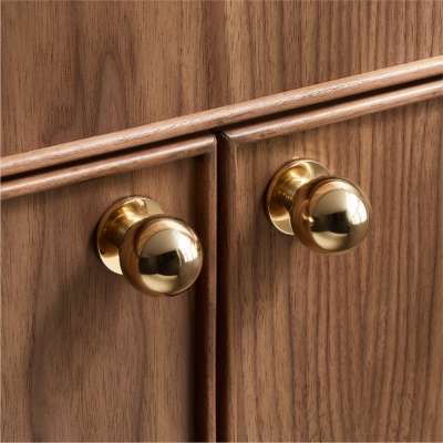 Wooden cabinet with shiny brass knobs, featuring a sleek, modern design perfect for enhancing home decor and storage solutions.