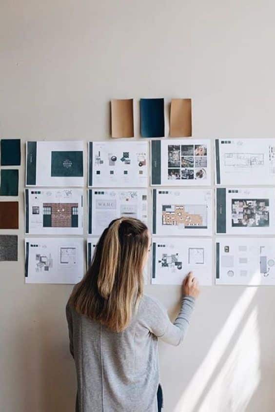 Designer reviewing project blueprints and color swatches on a wall, focused on creative planning and interior design layouts.
