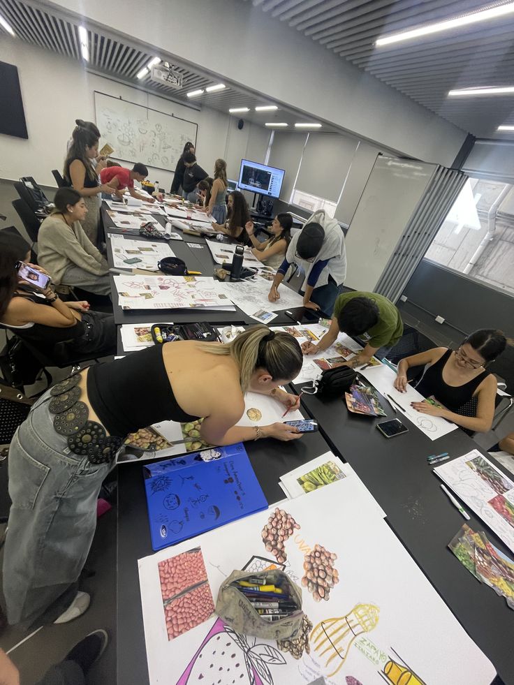 _ 1 Art students collaborate on a creative project in a classroom, surrounded by sketches and drawings on a long table. | Sky Rye Design Art students collaborate on a creative project in a classroom, surrounded by sketches and drawings on a long table.