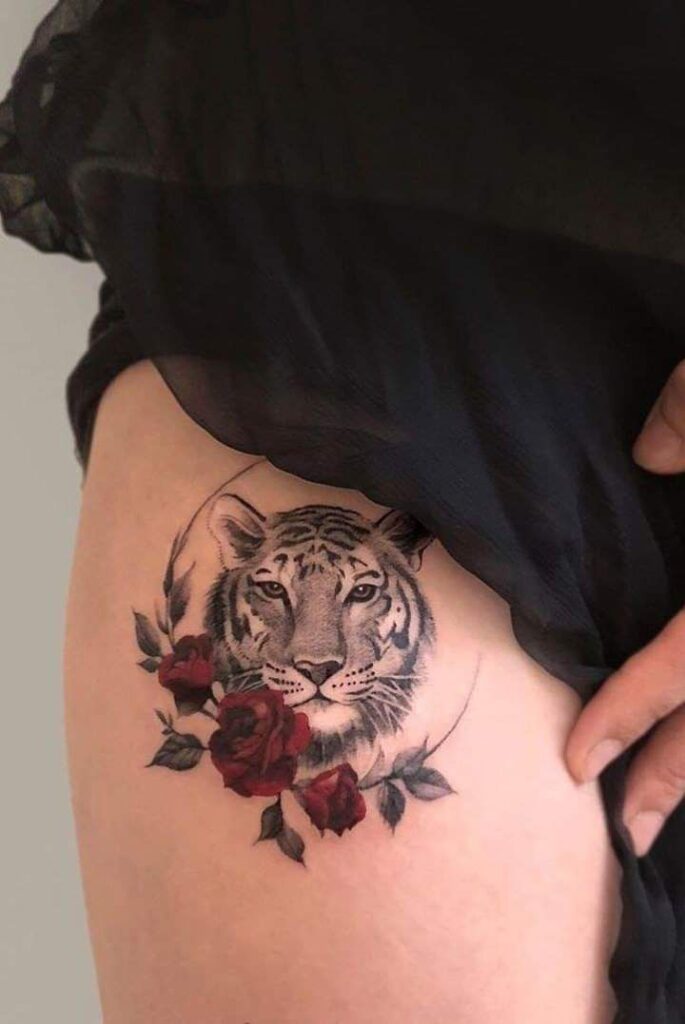 _ 1 Tiger tattoo with red roses on inner thigh, revealed under black fabric. | Sky Rye Design Tiger tattoo with red roses on inner thigh, revealed under black fabric.