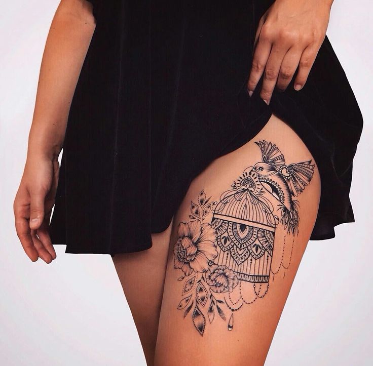_ 10 Black and white tattoo of a bird, cage, and flowers on a woman's thigh, artistic ink design showcasing intricate details. | Sky Rye Design Black and white tattoo of a bird, cage, and flowers on a woman's thigh, artistic ink design showcasing intricate details.