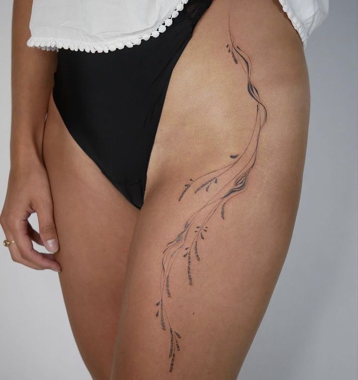_ 10 Minimalistic thigh tattoo with delicate lines and nature-inspired design on a person wearing black swimwear and a white top. | Sky Rye Design Minimalistic thigh tattoo with delicate lines and nature-inspired design on a person wearing black swimwear and a white top.