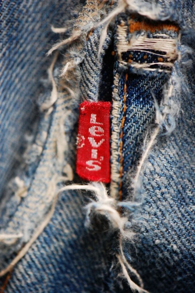 _ 10 Close-up of distressed blue denim with a red Levi's tag, showcasing rustic fashion appeal and iconic brand style. | Sky Rye Design Close-up of distressed blue denim with a red Levi's tag, showcasing rustic fashion appeal and iconic brand style.