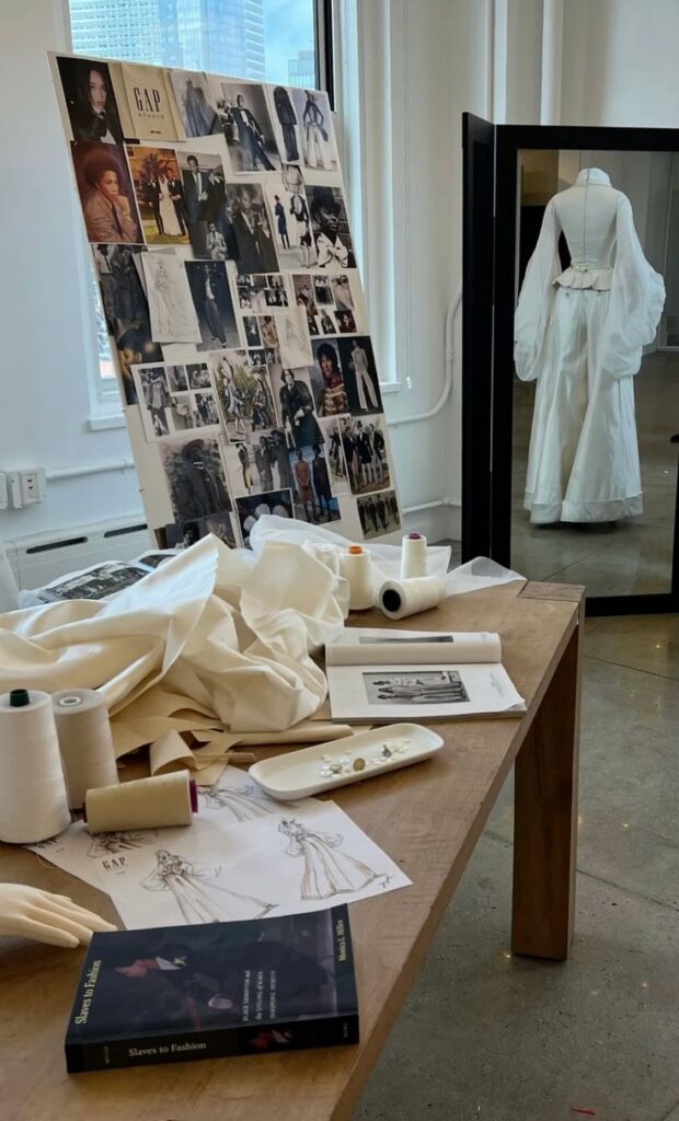 _ 10 Fashion studio with mood board, fabrics, and sketches on table. Mannequin displaying a white dress in background. Creative design space. | Sky Rye Design Fashion studio with mood board, fabrics, and sketches on table. Mannequin displaying a white dress in background. Creative design space.