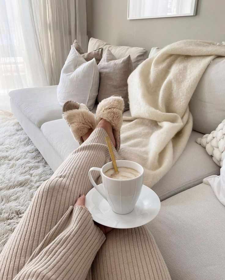 10 Scandinavian Interior Design Elements Cozy morning at home: person in fluffy slippers enjoys coffee on a chic beige sofa with plush pillows and a warm blanket. | Sky Rye Design Cozy morning at home: person in fluffy slippers enjoys coffee on a chic beige sofa with plush pillows and a warm blanket.