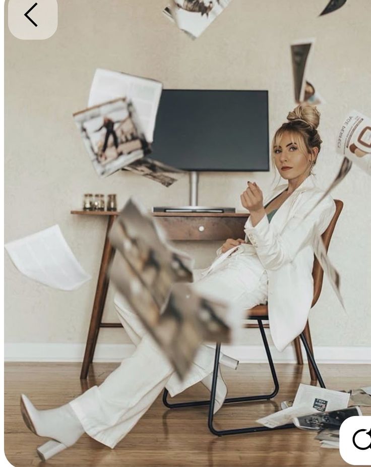 _ 11 Woman in white suit sits confidently amidst floating papers in modern living room, stylishly blending chaos and elegance. | Sky Rye Design Woman in white suit sits confidently amidst floating papers in modern living room, stylishly blending chaos and elegance.