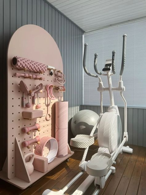 11 Home Gym Ideas To Make Yours More Pretty Functional - Wake Up For Fashion Stylish home gym with pink exercise equipment, yoga mat, balance ball, and elliptical machine on a wooden floor with natural light. | Sky Rye Design Stylish home gym with pink exercise equipment, yoga mat, balance ball, and elliptical machine on a wooden floor with natural light.