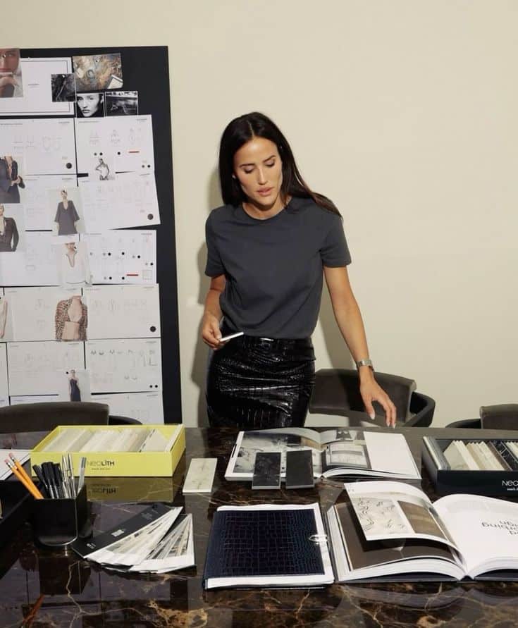 _ 13 Designer reviewing fashion sketches and fabric samples at a marble table, planning new collection in creative workspace. | Sky Rye Design Designer reviewing fashion sketches and fabric samples at a marble table, planning new collection in creative workspace.