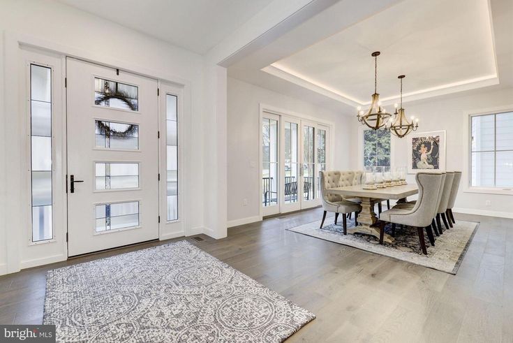 _ 14 Modern dining area with elegant chandelier, large windows, and stylish tufted chairs around a wooden table in a bright, spacious interior. | Sky Rye Design Modern dining area with elegant chandelier, large windows, and stylish tufted chairs around a wooden table in a bright, spacious interior.
