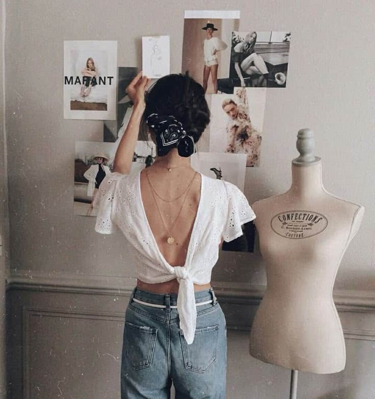 _ 15 Woman arranging fashion mood board, wearing backless top and jeans, next to a dress form mannequin in a stylish workspace. | Sky Rye Design Woman arranging fashion mood board, wearing backless top and jeans, next to a dress form mannequin in a stylish workspace.