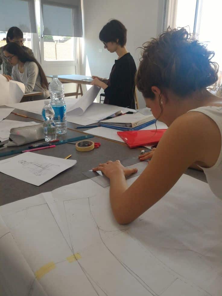 _ 16 Students in a design class working on fashion sketches and patterns, enhancing their skills in a light-filled studio environment. | Sky Rye Design Students in a design class working on fashion sketches and patterns, enhancing their skills in a light-filled studio environment.