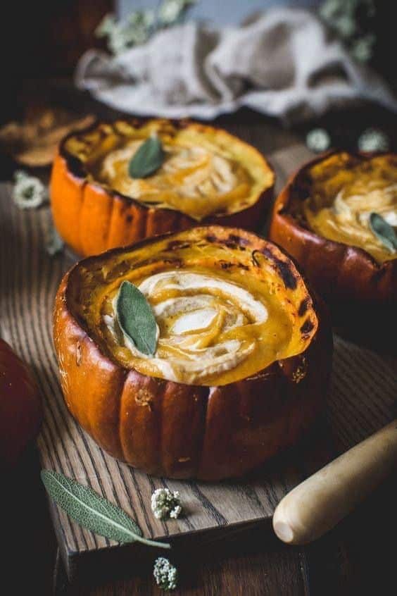 _ 16 Creamy pumpkin soup served in roasted pumpkin bowls, garnished with sage, on a rustic wooden table. Perfect for autumn meals. | Sky Rye Design Creamy pumpkin soup served in roasted pumpkin bowls, garnished with sage, on a rustic wooden table. Perfect for autumn meals.