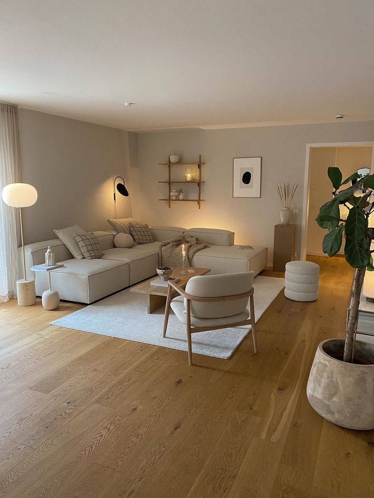 _ 17 Modern living room with neutral tones, featuring a cozy sectional sofa, wooden flooring, minimalist decor, and a potted plant for warmth. | Sky Rye Design Modern living room with neutral tones, featuring a cozy sectional sofa, wooden flooring, minimalist decor, and a potted plant for warmth.