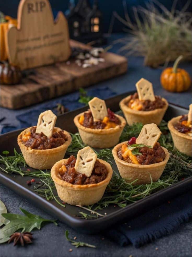 _ 19 Mini Halloween pumpkin pies with spooky tombstone cookies on a tray, surrounded by decorative herbs and pumpkins. | Sky Rye Design Mini Halloween pumpkin pies with spooky tombstone cookies on a tray, surrounded by decorative herbs and pumpkins.