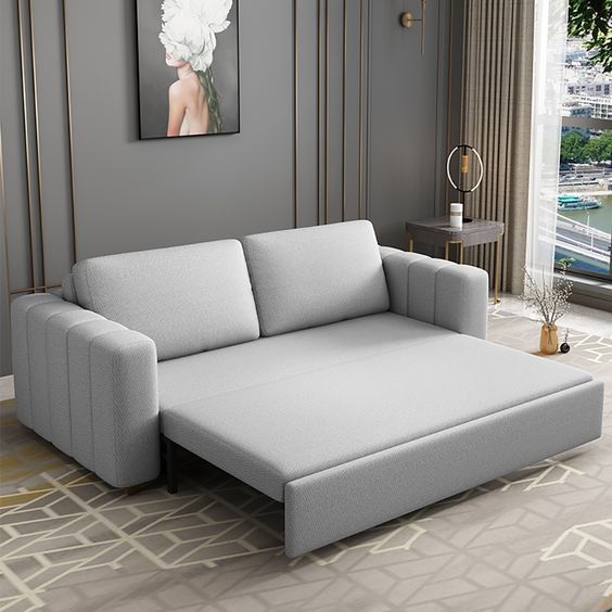 _ 19 Modern gray sofa bed unfolded in a stylish living room with a city view, patterned rug, and elegant wall art. | Sky Rye Design Modern gray sofa bed unfolded in a stylish living room with a city view, patterned rug, and elegant wall art.