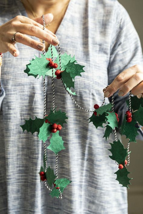 1fd7c5d00859f9f01e839cded56ba986 Person hanging a festive wreath with green leaves and red berries on a striped shirt, showcasing holiday decor and DIY craft ideas. | Sky Rye Design Person hanging a festive wreath with green leaves and red berries on a striped shirt, showcasing holiday decor and DIY craft ideas.