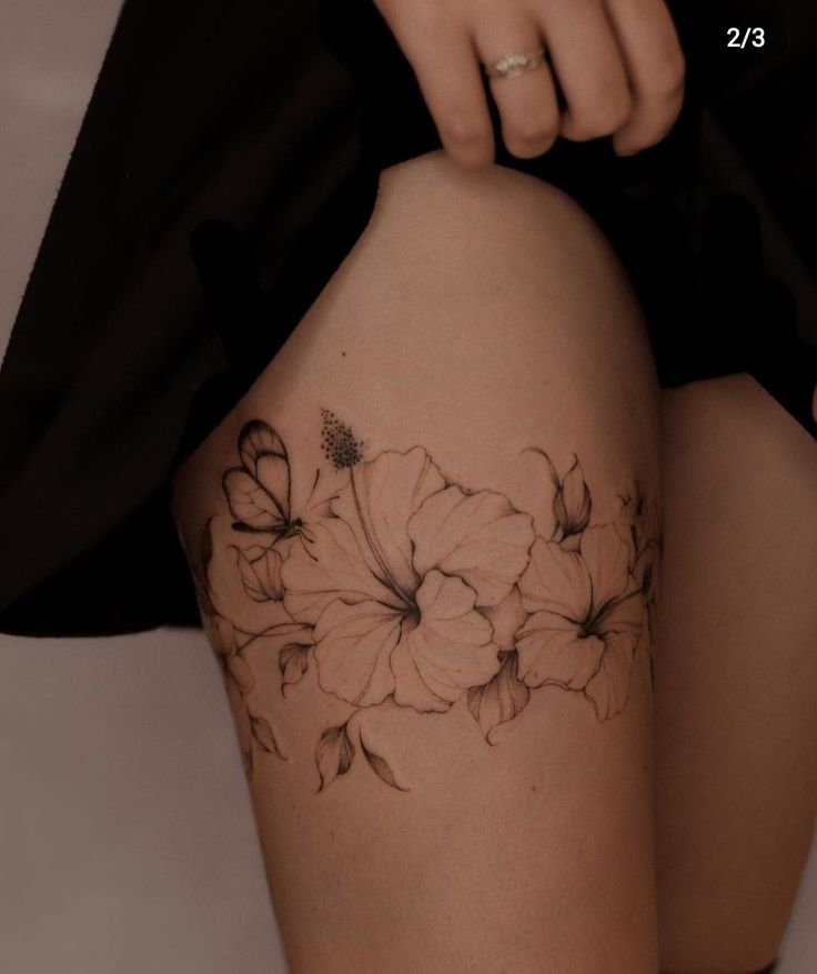 _ 2 Thigh tattoo featuring delicate hibiscus flowers and a butterfly in black ink design. Ideal inspiration for elegant and feminine tattoo ideas. | Sky Rye Design Thigh tattoo featuring delicate hibiscus flowers and a butterfly in black ink design. Ideal inspiration for elegant and feminine tattoo ideas.