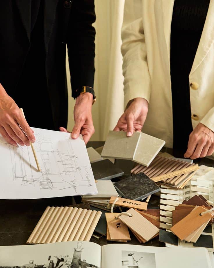 _ 2 Architects reviewing material samples and design sketches on a table, with various textures and color swatches laid out for selection. | Sky Rye Design Architects reviewing material samples and design sketches on a table, with various textures and color swatches laid out for selection.