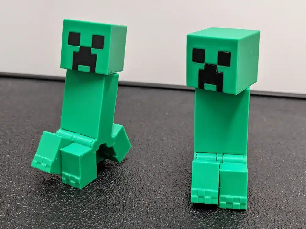 Two green blocky figures resembling characters from a popular video game, standing on a black surface.