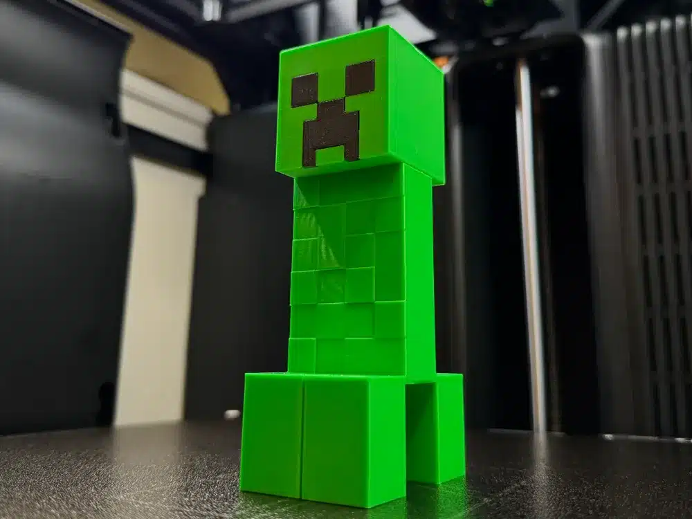 2025-07-31_aeaea2da22e4b 3D-printed green Creeper from Minecraft on a table, showcasing blocky design and iconic pixel face in a room setting. | Sky Rye Design 3D-printed green Creeper from Minecraft on a table, showcasing blocky design and iconic pixel face in a room setting.
