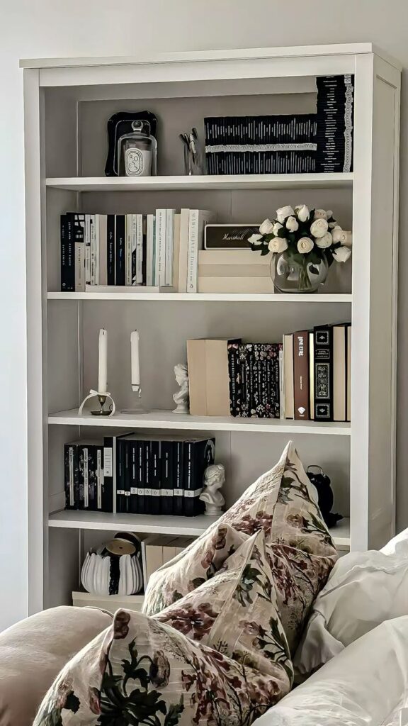 _ - 2025-12-01T203443702 Elegant white bookshelf with books, decor, and flowers; cozy floral pillows in foreground. Perfect for a stylish home interior. | Sky Rye Design Elegant white bookshelf with books, decor, and flowers; cozy floral pillows in foreground. Perfect for a stylish home interior.