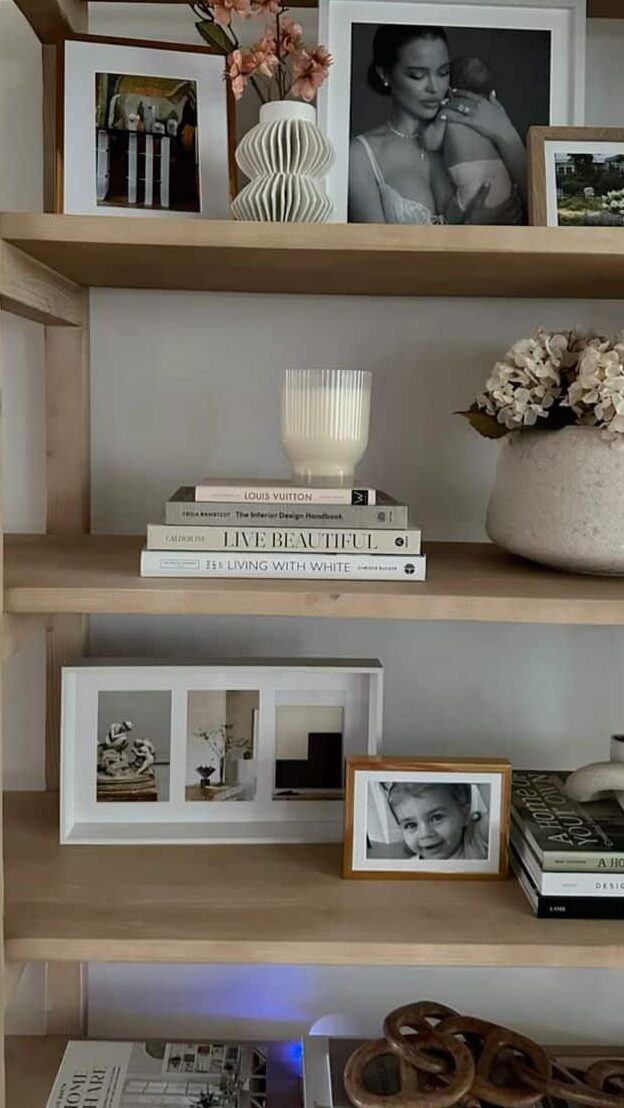 _ - 2025-12-01T204542859 Stylish wooden bookshelf with framed photos, decorative vases, and design books, adding a cozy and elegant touch to the home decor. | Sky Rye Design Stylish wooden bookshelf with framed photos, decorative vases, and design books, adding a cozy and elegant touch to the home decor.