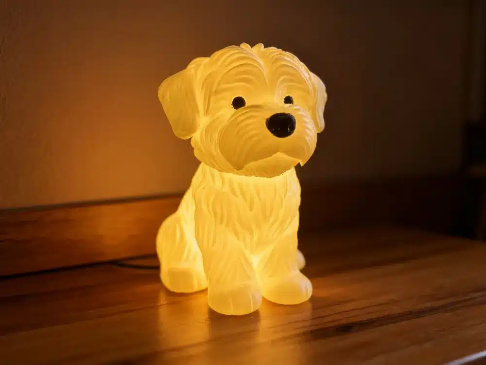 Illuminated puppy-shaped night light on a wooden surface, emitting a warm glow for cozy, decorative ambiance in a room.