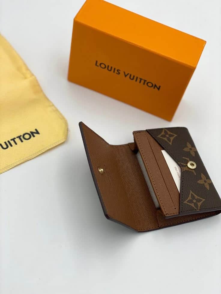 Louis Vuitton wallet with monogram design, accompanied by an orange box and dust bag, displayed on a white surface.