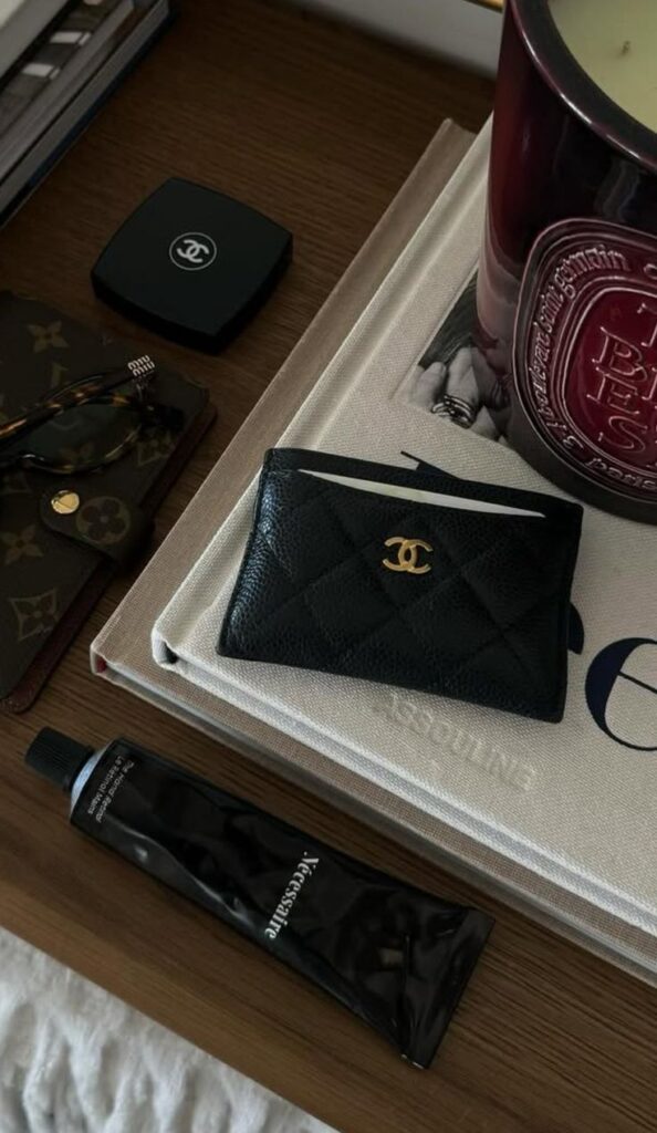 Luxurious tabletop display with designer wallet, candle, sunglasses, and cream tube on books. Elegant, stylish, and sophisticated setup.