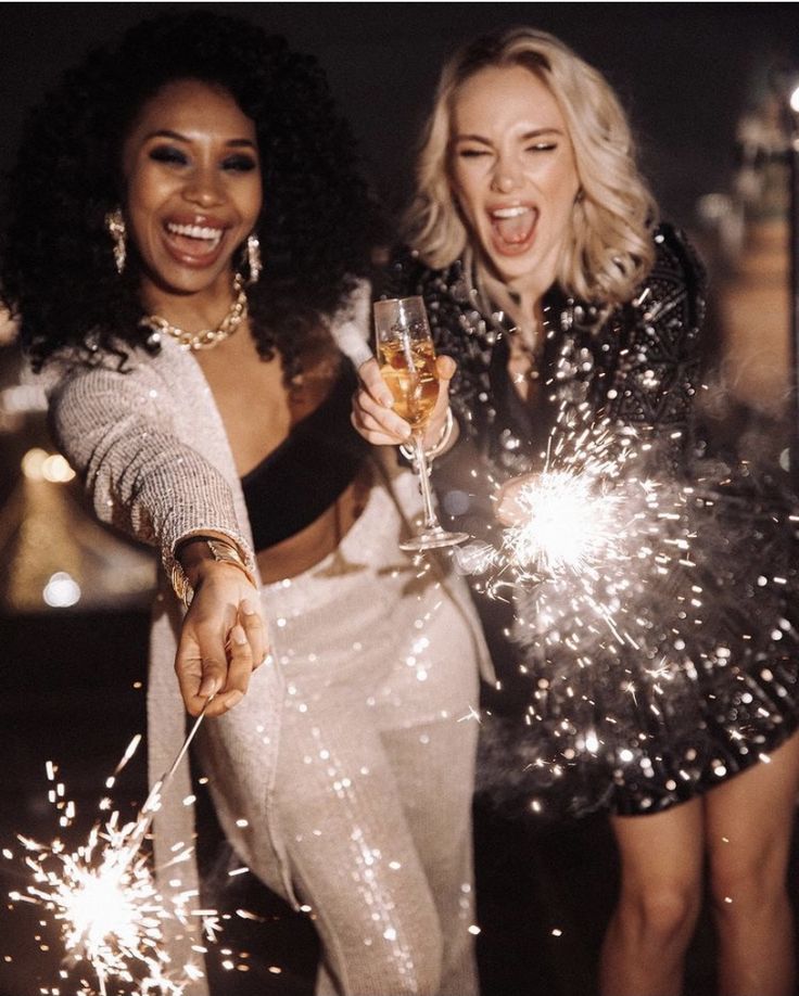 _ - 2025-12-04T131152140 Two women celebrating with sparklers and champagne, smiling joyfully in festive outfits during a nighttime party. | Sky Rye Design Two women celebrating with sparklers and champagne, smiling joyfully in festive outfits during a nighttime party.