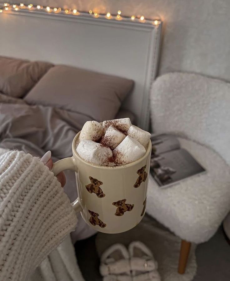 _ - 2025-12-04T133009718 Cozy bedroom scene with a hand holding a teddy bear mug filled with marshmallow hot chocolate, soft bed, and warm lighting. Perfect winter vibes. | Sky Rye Design Cozy bedroom scene with a hand holding a teddy bear mug filled with marshmallow hot chocolate, soft bed, and warm lighting. Perfect winter vibes.
