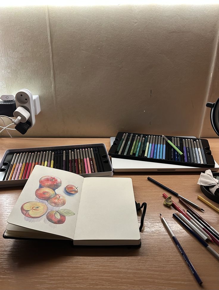 Art desk with sketchbook and colored pencils, featuring a peach illustration in progress, under warm lighting.