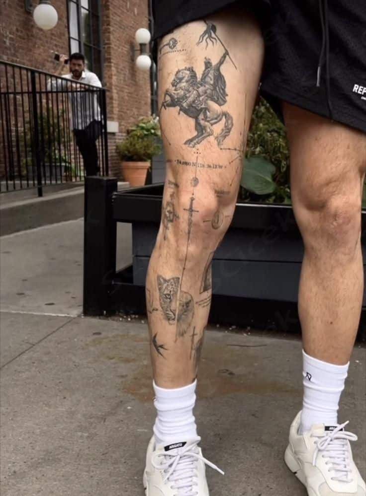Detailed leg tattoos featuring a lion, horse, and sword designs, displayed outdoors with a brick wall and plants in the background.
