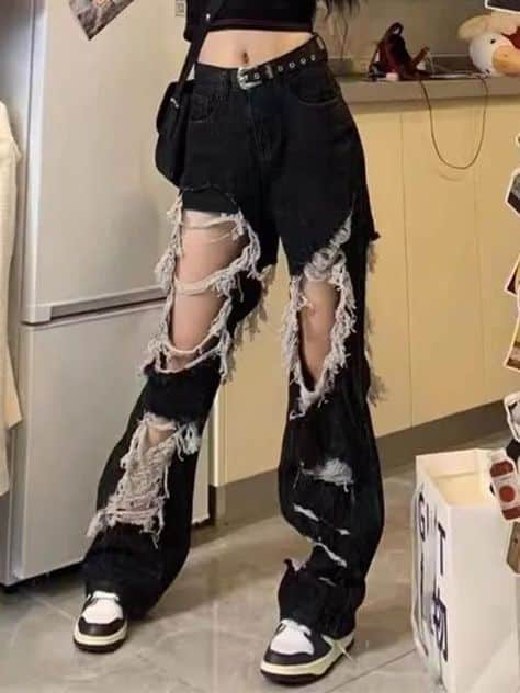 Trendy outfit featuring black ripped jeans and sneakers, perfect for a casual, edgy street style look in a modern kitchen setting.