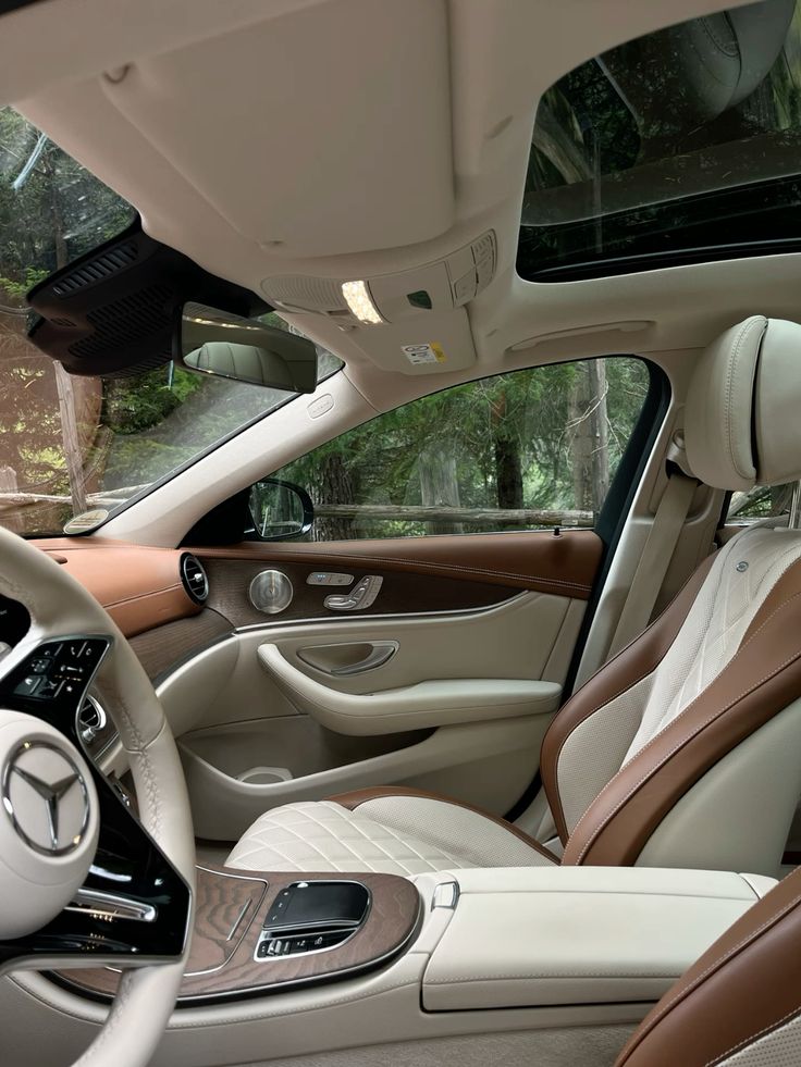 Luxurious car interior featuring premium leather seats, wood accents, and a panoramic sunroof, offering elegant comfort and style.