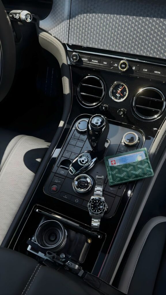Luxury car interior featuring a sleek gear shift, elegant watch, and a camera, showcasing sophistication and style.