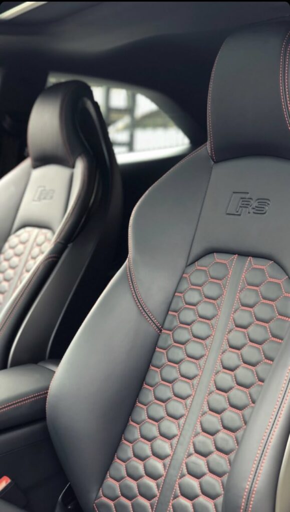 Luxury black leather car seats with red stitching and honeycomb pattern, featuring RS logo for a premium driving experience.