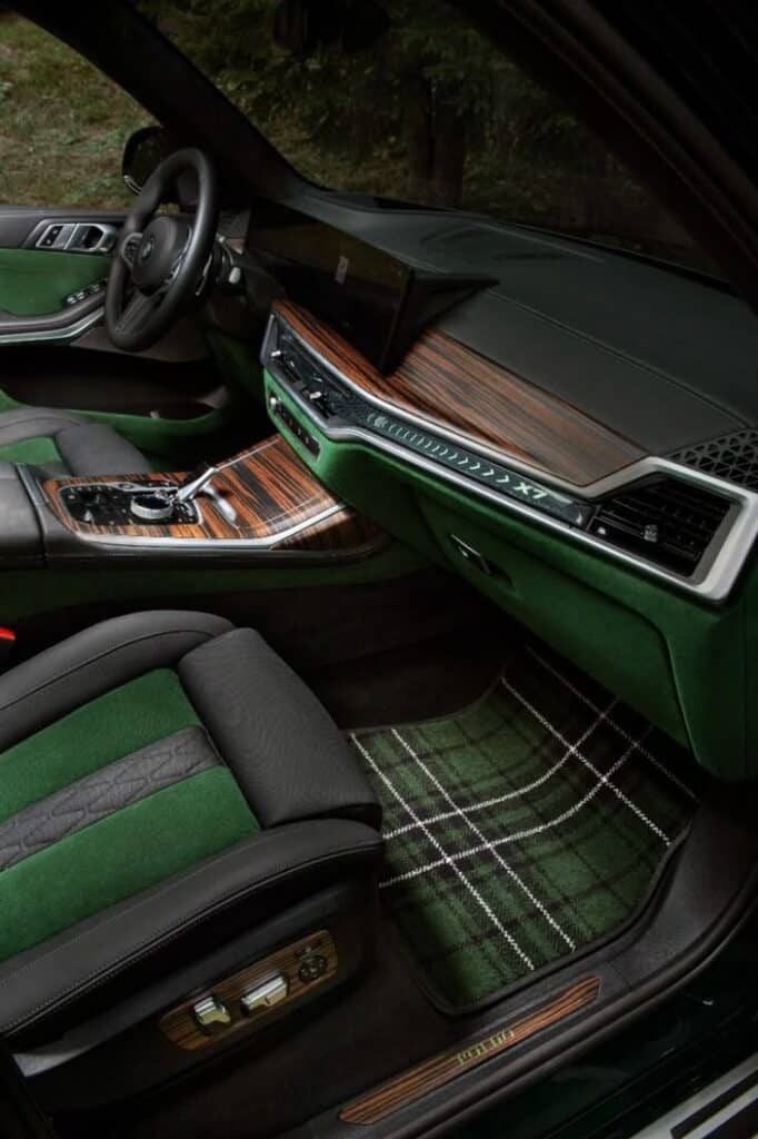 Luxurious car interior with green and black upholstery, wooden accents, and plaid floor mats, highlighting elegance and modern design.