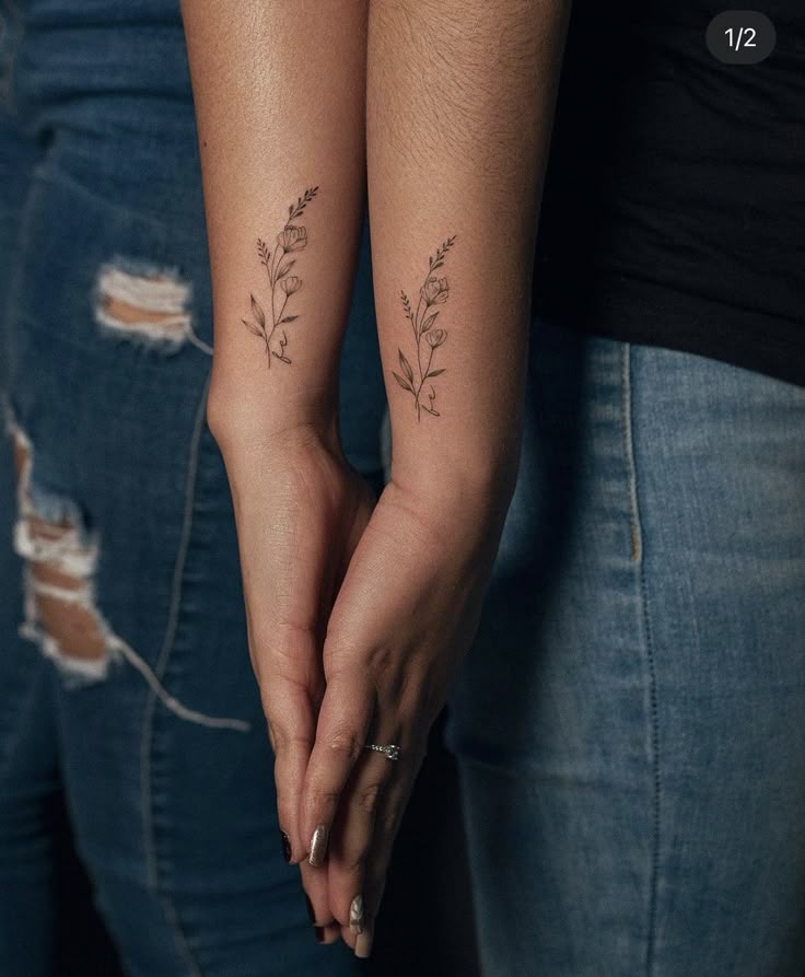 _ - 2025-12-12T144358674 Two people holding hands, showing matching delicate flower tattoos on their forearms, wearing casual denim and black clothes. | Sky Rye Design Two people holding hands, showing matching delicate flower tattoos on their forearms, wearing casual denim and black clothes.