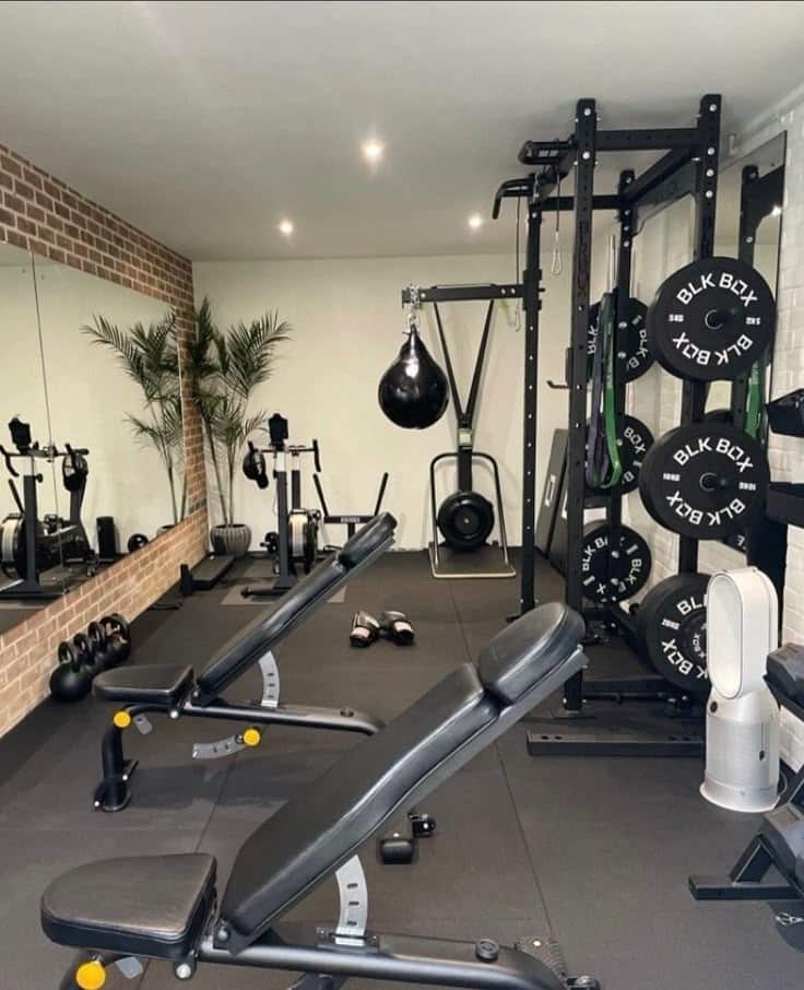 _ - 2025-12-16T183737904 Modern home gym with benches, weights, and a punching bag, reflecting a stylish workout space with mirrors and greenery. | Sky Rye Design Modern home gym with benches, weights, and a punching bag, reflecting a stylish workout space with mirrors and greenery.