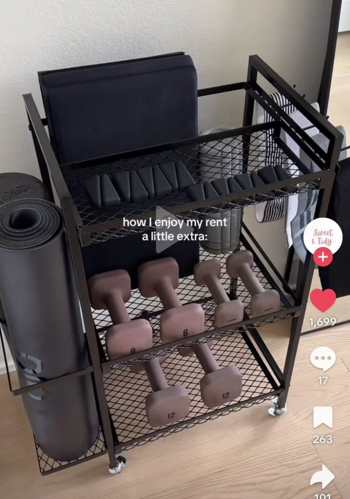 Screenshot Home gym organization cart with dumbbells, yoga mat, and accessories neatly arranged, perfect for compact fitness spaces. | Sky Rye Design Home gym organization cart with dumbbells, yoga mat, and accessories neatly arranged, perfect for compact fitness spaces.