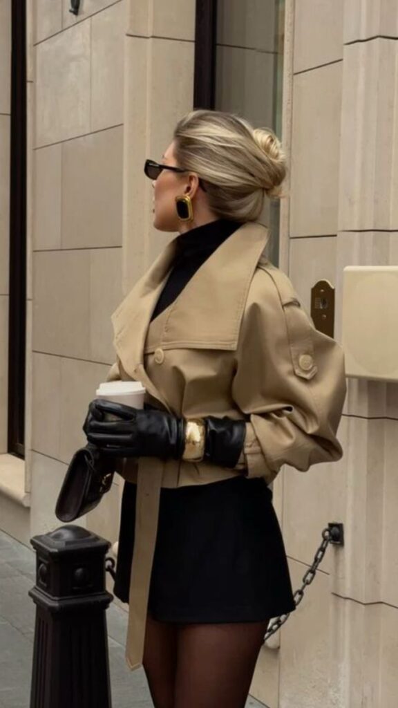 _ - 2025-12-28T122242565 Fashionable woman in a beige trench coat and sunglasses holds a coffee cup, showcasing an elegant city style against a stone building backdrop. | Sky Rye Design Fashionable woman in a beige trench coat and sunglasses holds a coffee cup, showcasing an elegant city style against a stone building backdrop.