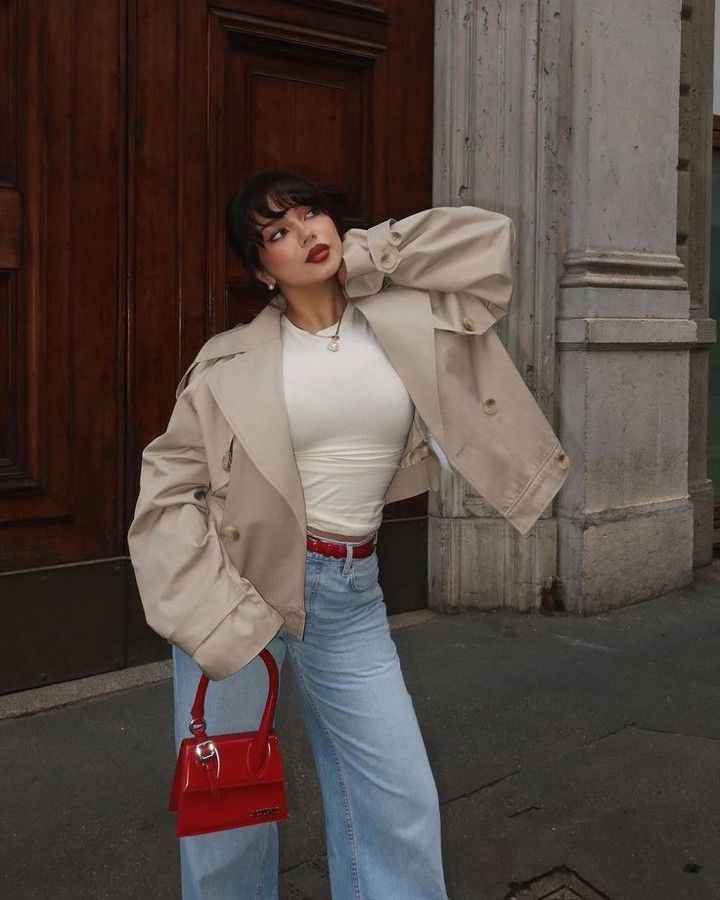 _ - 2025-12-28T122641391 Fashionable woman in beige jacket and jeans, holding a red handbag, poses stylishly against an urban backdrop. Casual chic street style. | Sky Rye Design Fashionable woman in beige jacket and jeans, holding a red handbag, poses stylishly against an urban backdrop. Casual chic street style.