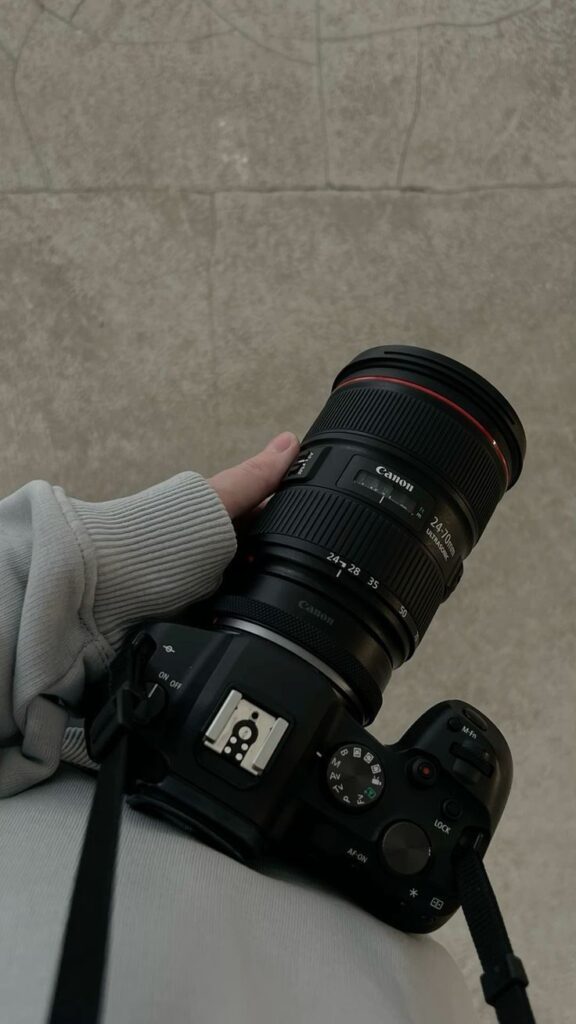 _ - 2025-12-28T133650567 Person holding a Canon camera with a zoom lens, wearing a gray sweatshirt, over a textured background. Perfect for photography enthusiasts. | Sky Rye Design Person holding a Canon camera with a zoom lens, wearing a gray sweatshirt, over a textured background. Perfect for photography enthusiasts.