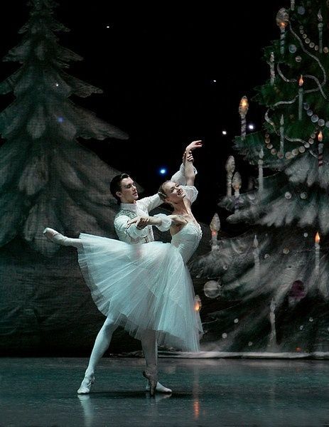 _ - 2025-12-28T140721182 Ballet dancers perform gracefully on stage in winter-themed costumes, set against a backdrop of trees and festive decorations. | Sky Rye Design Ballet dancers perform gracefully on stage in winter-themed costumes, set against a backdrop of trees and festive decorations.