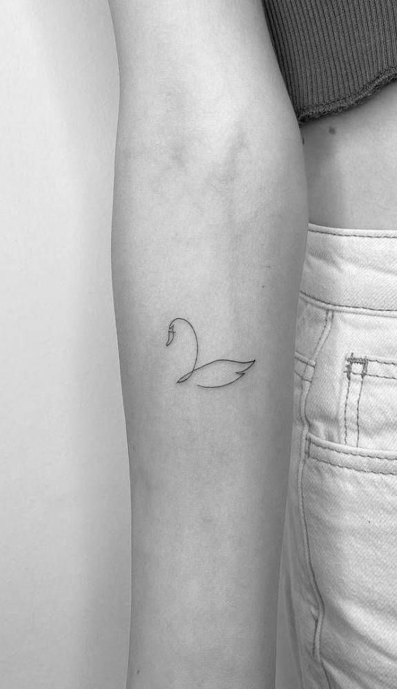 _ - 2025-12-28T162758699 Minimalist swan tattoo on a forearm in black ink, showcasing delicate line art on a person wearing a sleeveless top and light pants. | Sky Rye Design Minimalist swan tattoo on a forearm in black ink, showcasing delicate line art on a person wearing a sleeveless top and light pants.