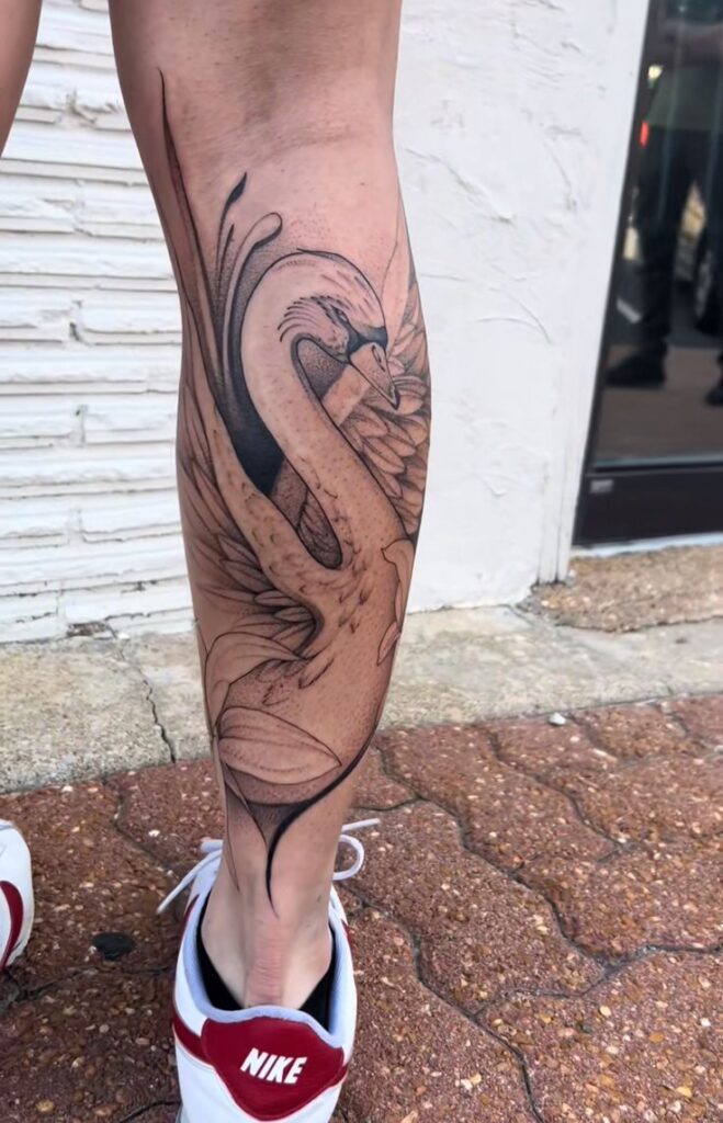 _ - 2025-12-28T164640559 Elegant swan tattoo on a person's leg, showcasing intricate feather details, paired with red and white Nike shoes. | Sky Rye Design Elegant swan tattoo on a person's leg, showcasing intricate feather details, paired with red and white Nike shoes.