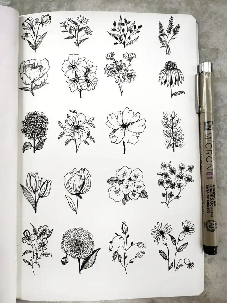 Hand-drawn floral sketches in black ink fill a notebook page, showcasing various simple flower designs. A Micron pen lies beside the artwork.